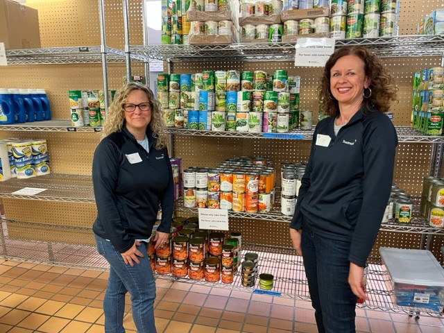 Two Trustmark associates standing in front of racks with canned goods.