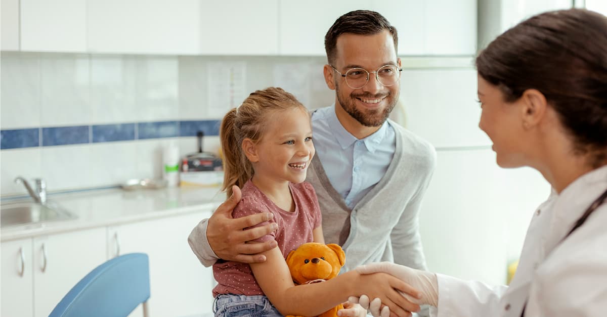 Man and young child meeting a doctor in a medical office.