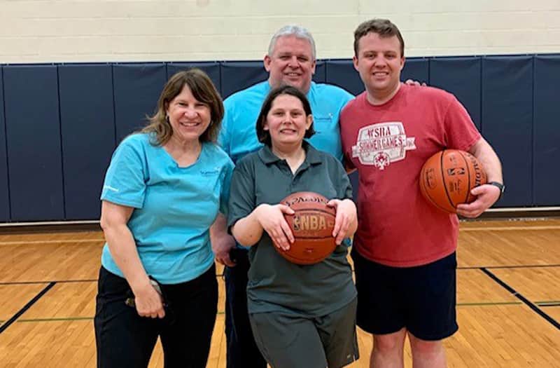 Four people posing on a basketball court