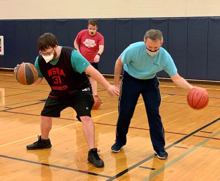 Two basketball players dribbling on the court