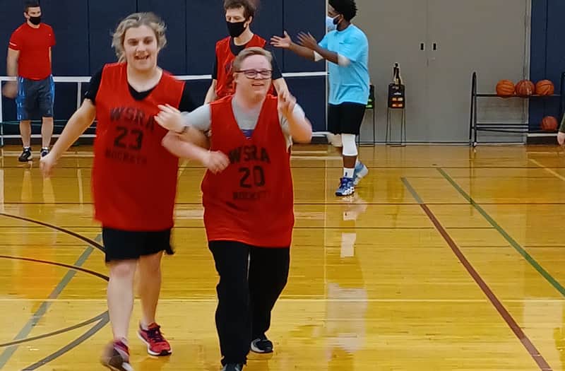 Two basketball players running across the court