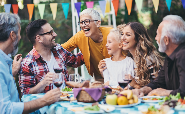 Family gathered around table for a backyard party.
