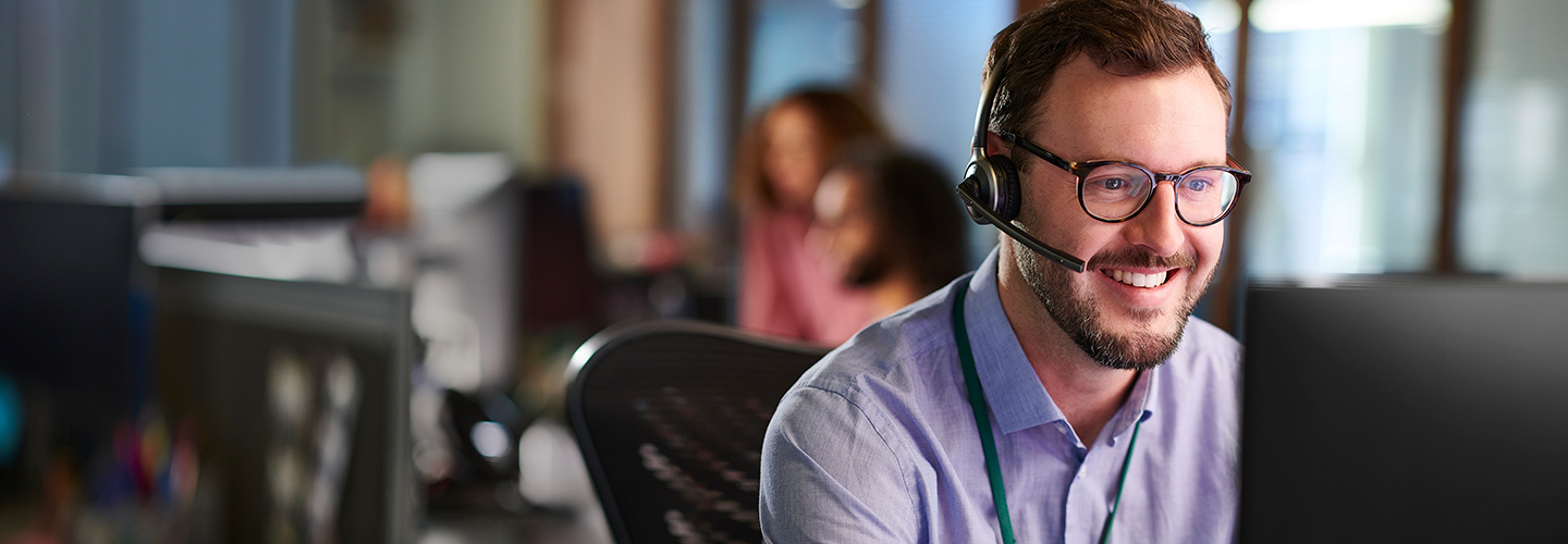 Customer service representative with a headset and working at a computer